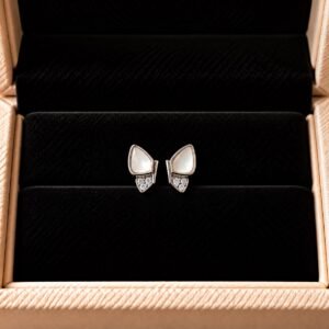 Asymmetrical mother-of-pearl earrings with pavé diamond detailing on black velvet